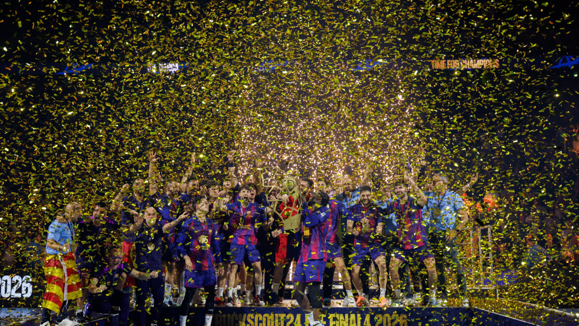 A group of athletes celebrate on a podium surrounded by falling golden confetti, holding a trophy and raising their arms in victory.